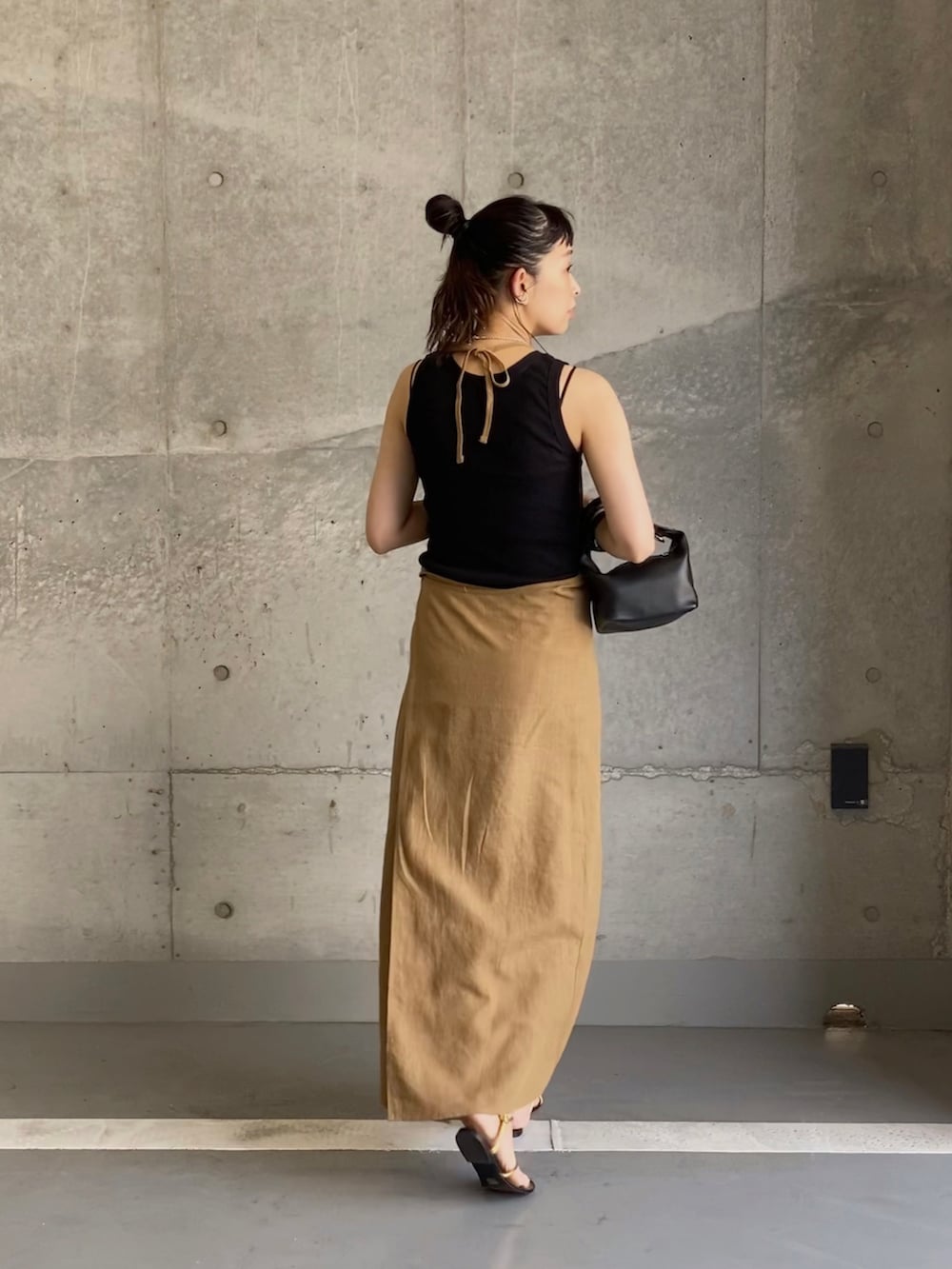 ベージュ系のワンピース、ゴールド系のサンダル、ブラック系のハンドバッグを着用したレディースの夏コーディネートの2枚目の写真