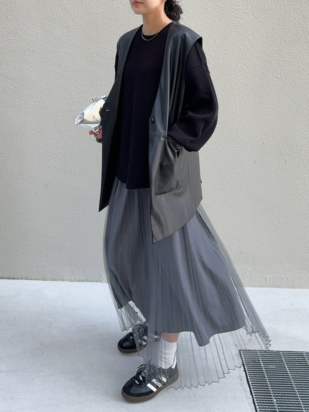 ブラック系のスカート、シルバー系のショルダーバッグ、ブラック系のスニーカーを着用したレディースの春コーディネートの3枚目の写真