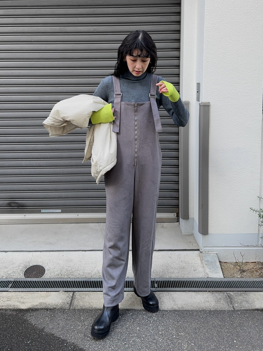 グレー系のサロペット/オーバーオール、グレー系のニット/セーター、ブラック系のブーツを着用したレディースの冬コーディネートの2枚目の写真