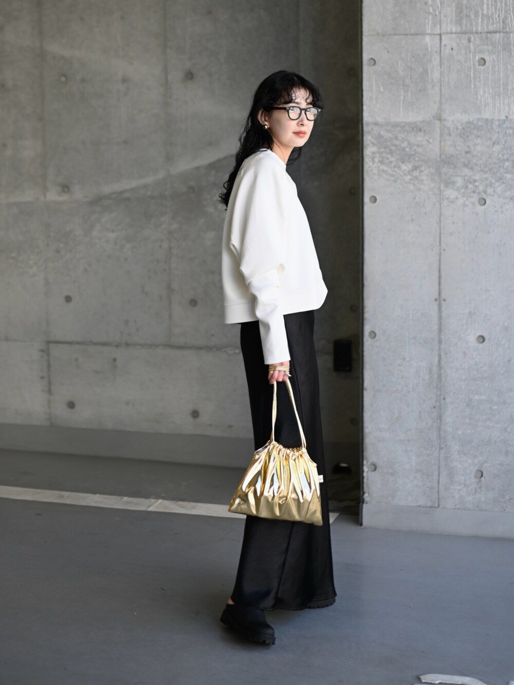ホワイト系のスウェット、ブラック系のスカート、ゴールド系のショルダーバッグを着用したレディースの春コーディネートの2枚目の写真