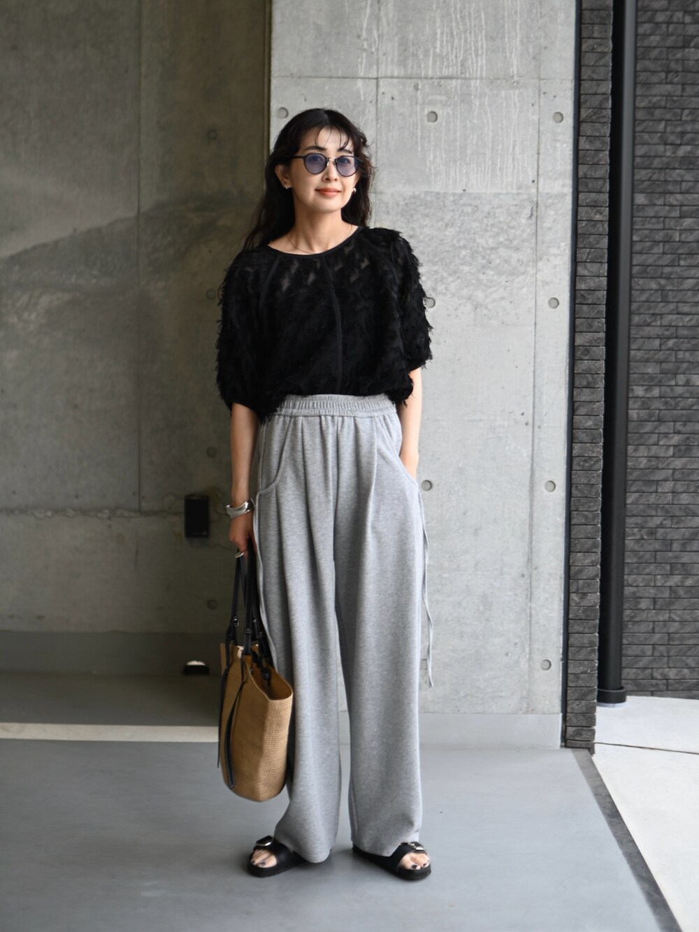 ブラック系のシャツ/ブラウス、ベージュ系のトートバッグ、グレー系のスウェットパンツを着用したレディースの夏コーディネートの2枚目の写真