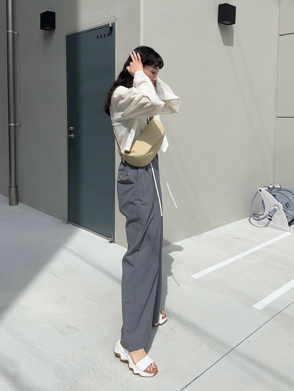 ホワイト系のシャツ/ブラウス、ベージュ系のショルダーバッグ、グレー系のスラックスを着用したレディースの春コーディネートの3枚目の写真