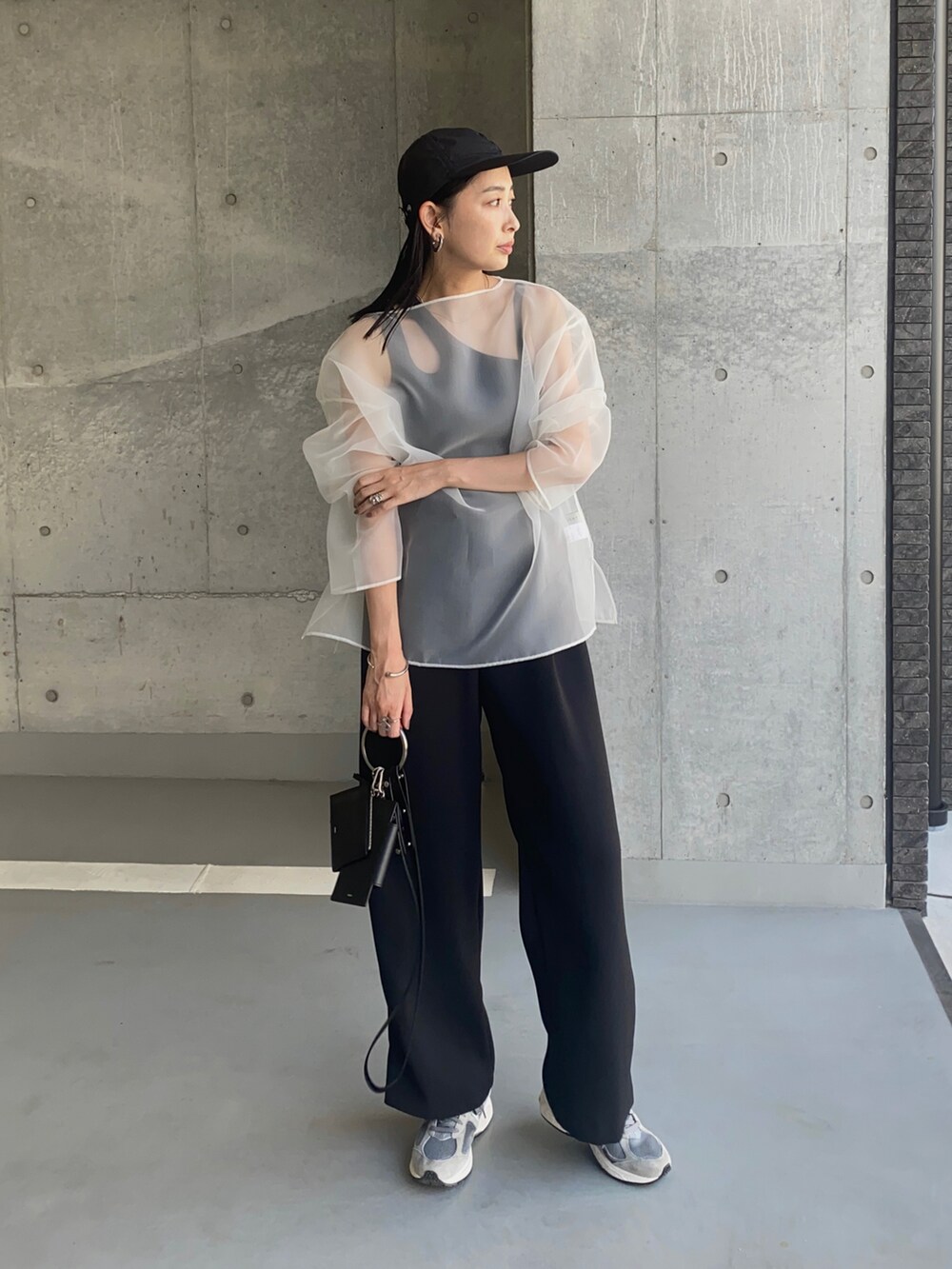 ブラック系のショルダーバッグ、グレー系のスニーカー、ホワイト系のシャツ/ブラウスを着用したレディースの夏コーディネートの2枚目の写真