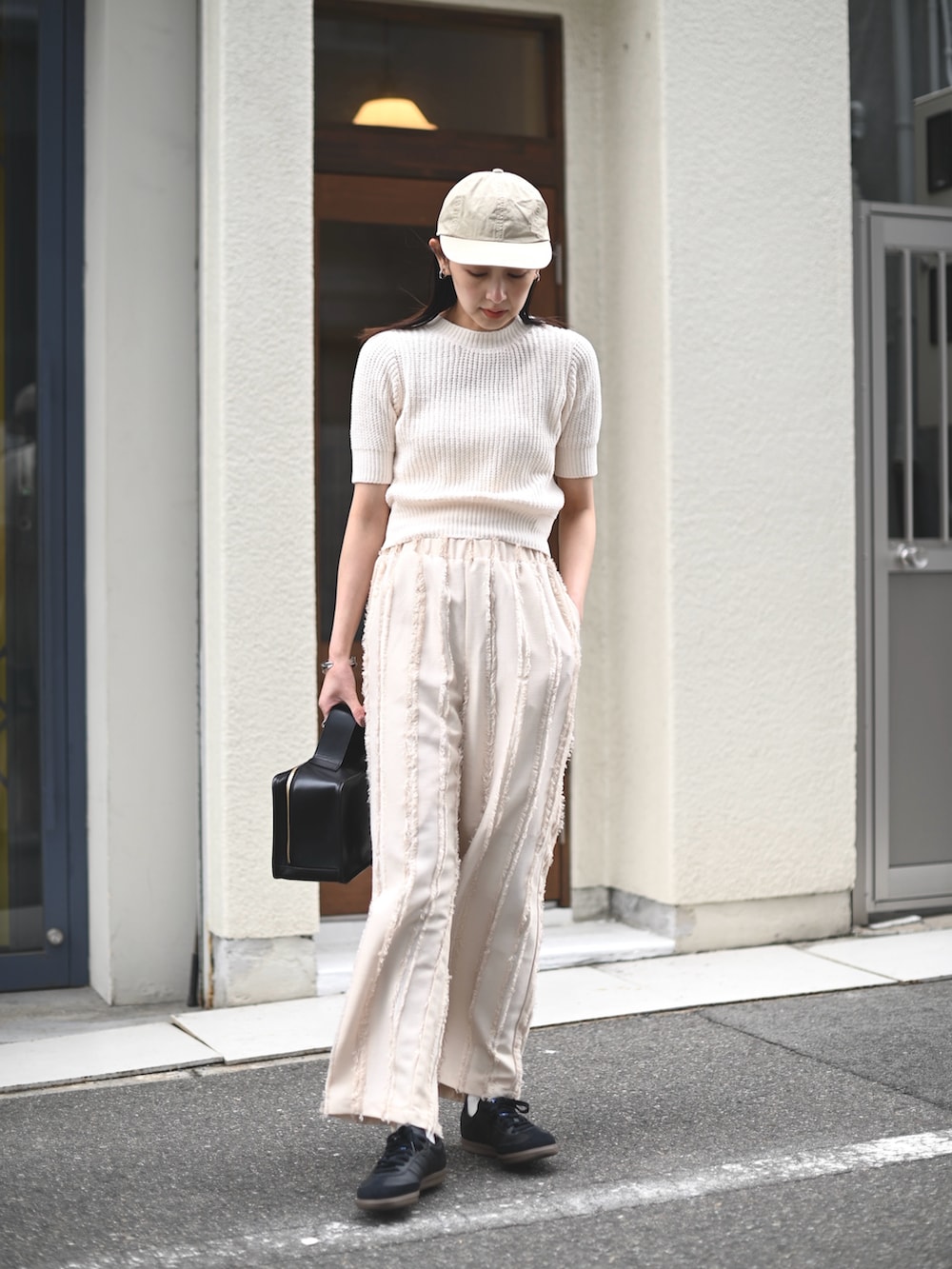 ホワイト系のニット/セーター、ホワイト系のその他パンツ、ブラック系のスニーカーを着用したレディースの春コーディネートの3枚目の写真