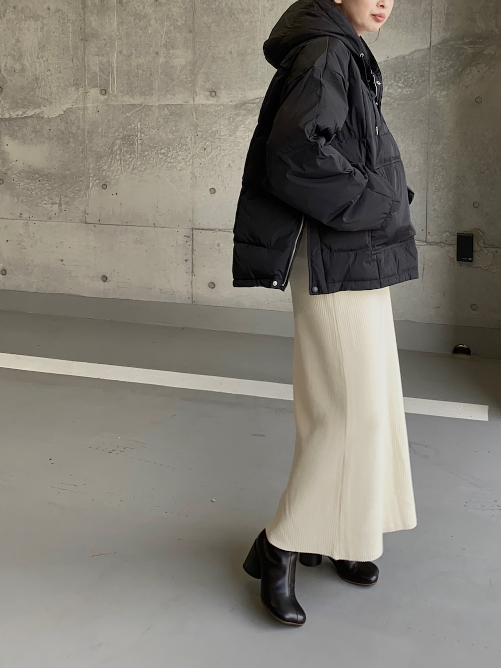 ブラック系のダウンジャケット/コート、ホワイト系のスカート、シルバー系のネックレスを着用したレディースの冬コーディネートの2枚目の写真