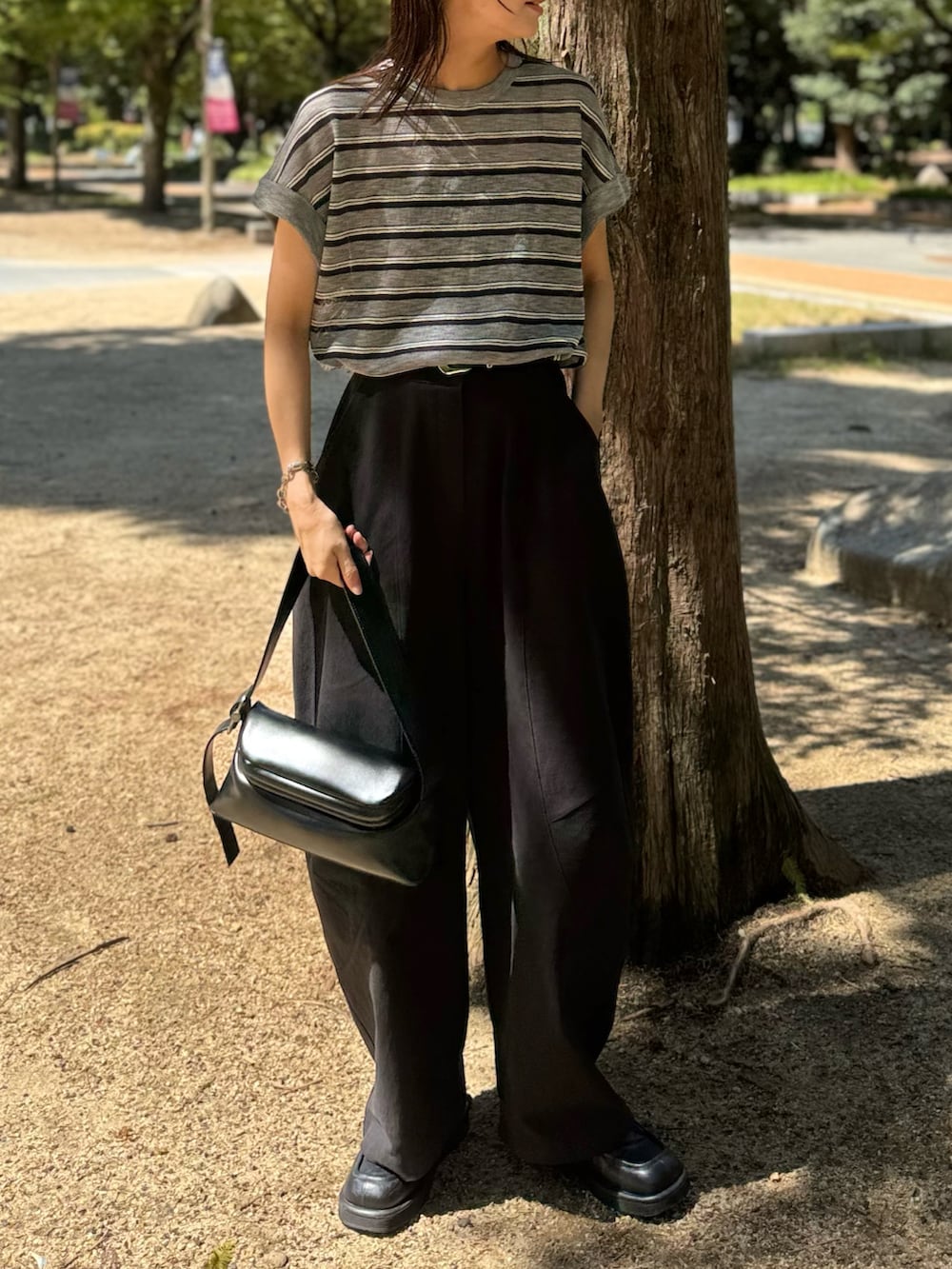 ブラック系のショルダーバッグ、ブラック系のチノパンツ、ブラック系のローファーを着用したレディースの秋コーディネートの3枚目の写真