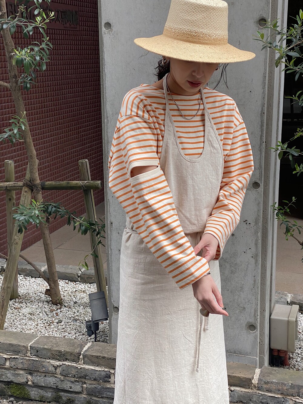 オレンジ系のTシャツ/カットソー、ベージュ系のハット、ブラウン系の口紅/リップティント/グロスを着用したレディースの春コーディネートの3枚目の写真