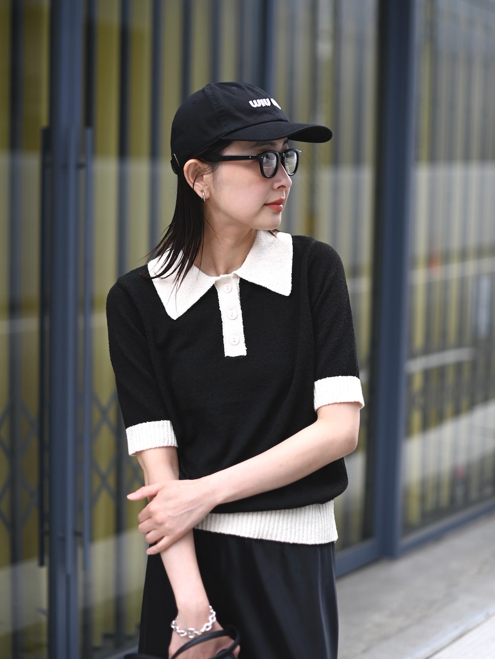 ブラック系のニット/セーター、ブラック系のスカート、ブラック系のスニーカーを着用したレディースの春コーディネートの2枚目の写真