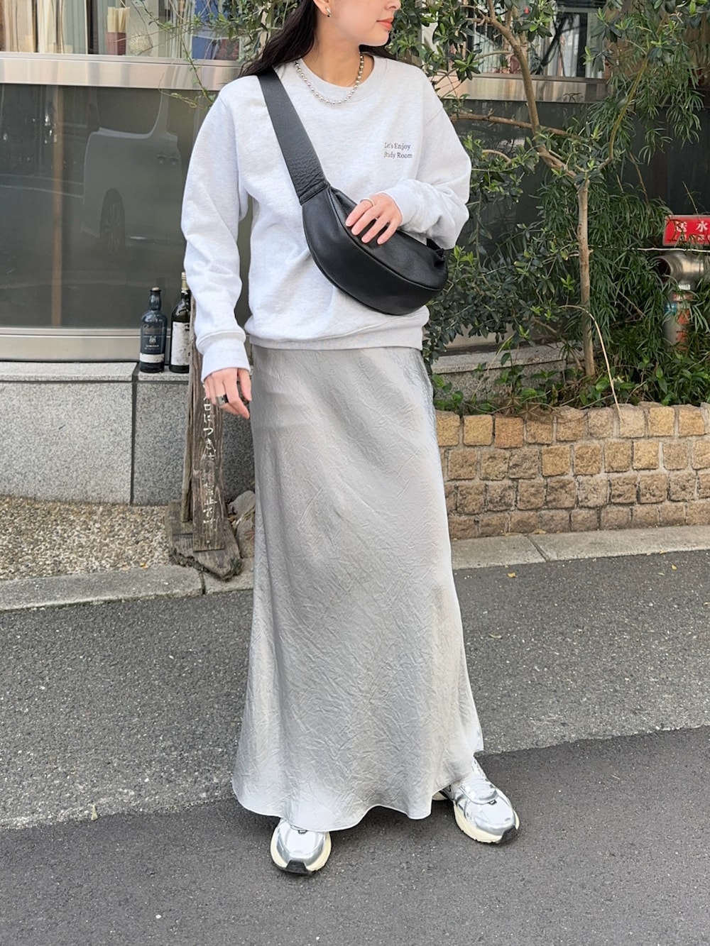 グレー系のスウェット、シルバー系のスカート、ホワイト系のスニーカーを着用したレディースの春コーディネートの3枚目の写真