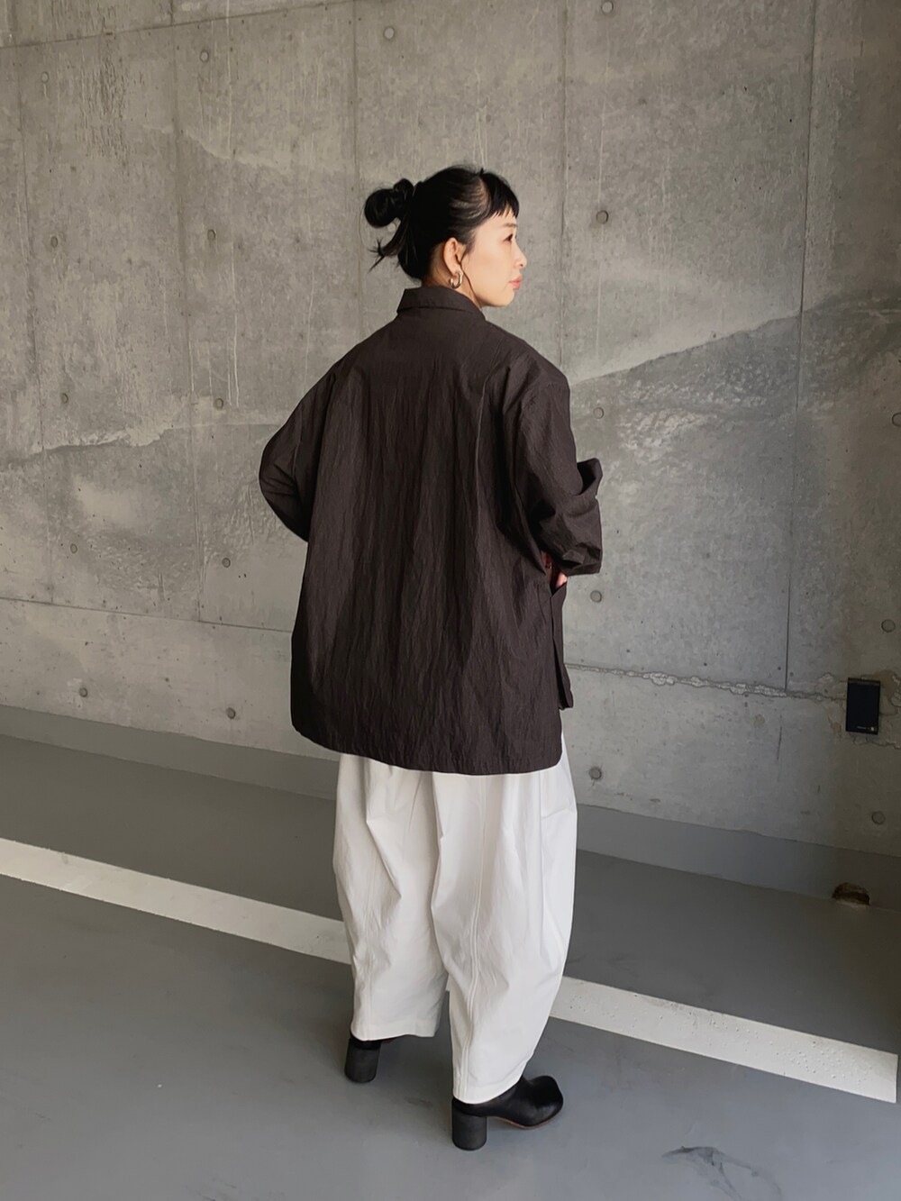 ブラック系のナイロンジャケット、ホワイト系のチノパンツ、ブラック系のブーツを着用したレディースの冬コーディネートの3枚目の写真