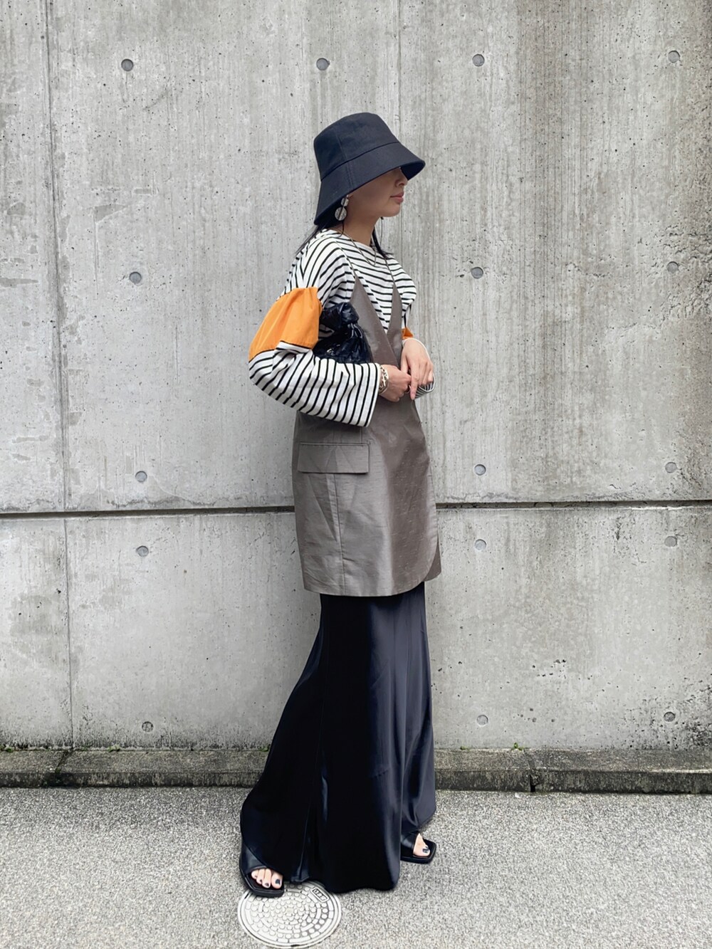 オレンジ系のTシャツ/カットソー、ベージュ系のキャミソール、ブラック系のスカートを着用したレディースの春コーディネートの4枚目の写真