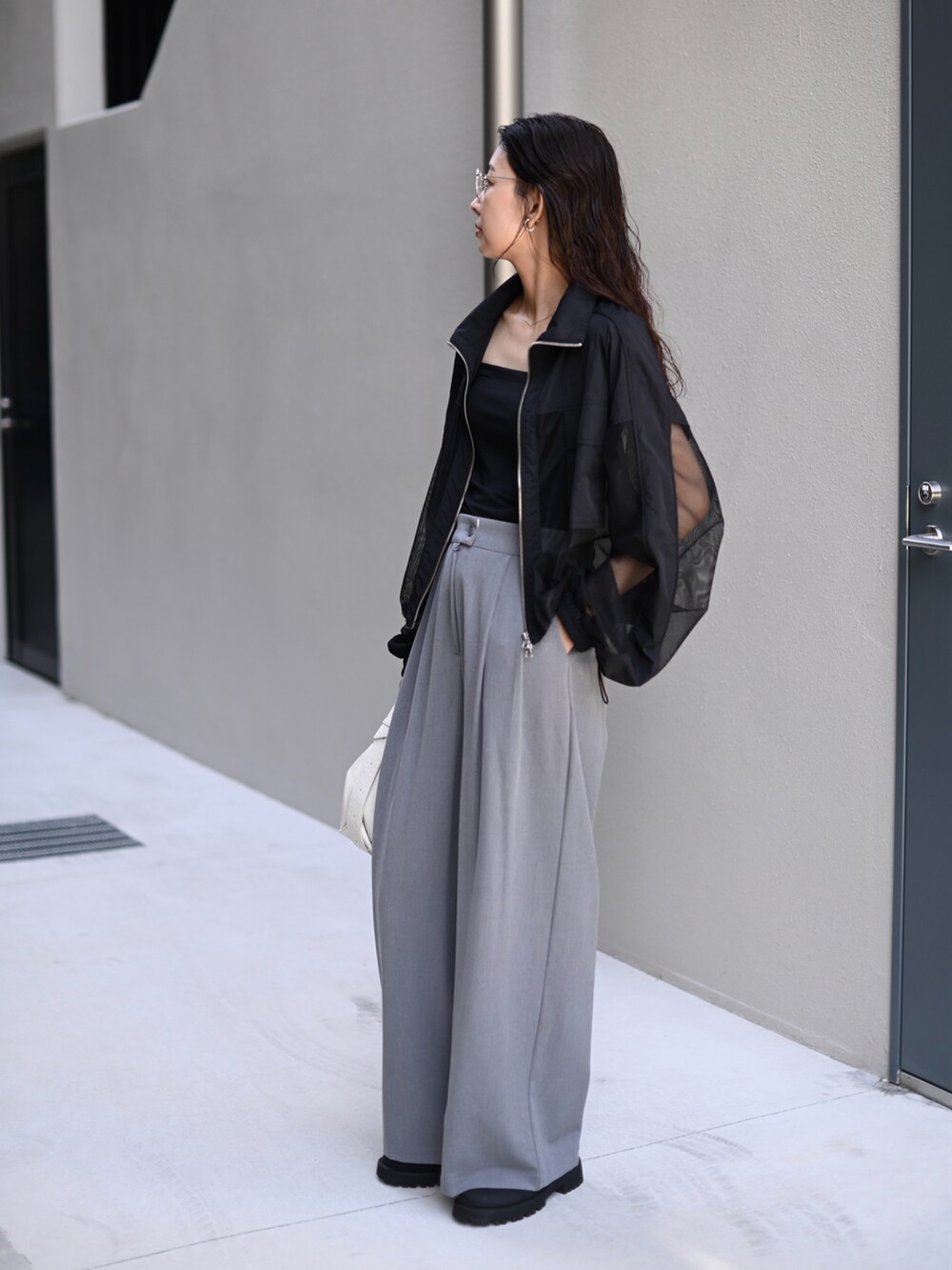 ブラック系のブルゾン、ホワイト系のショルダーバッグ、ブラック系のスリッポンを着用したレディースの秋コーディネートの4枚目の写真