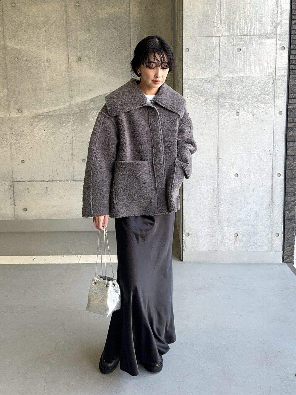 グレー系のその他アウター、シルバー系のショルダーバッグ、ブラック系のスカートを着用したレディースの冬コーディネートの2枚目の写真