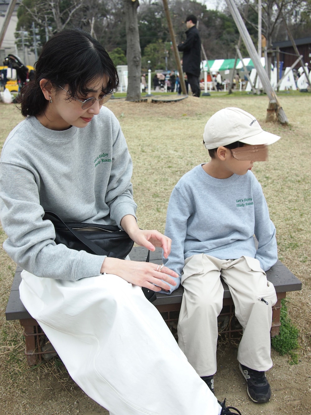 グレー系のスウェット、ブラック系のスニーカー、ホワイト系のチノパンツを着用したレディースの春コーディネートの3枚目の写真