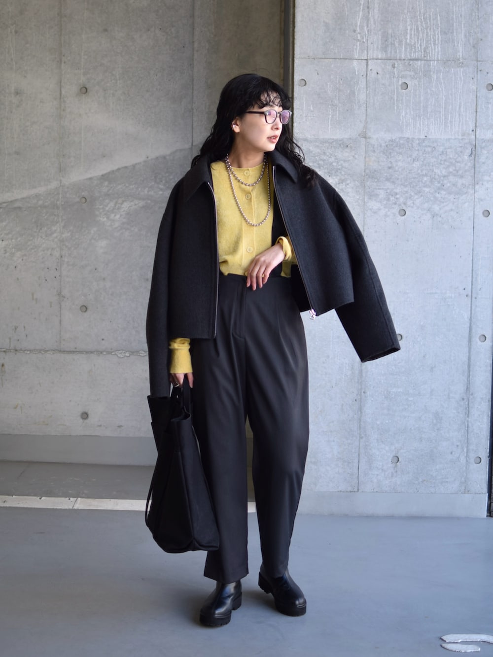 グレー系のブルゾン、イエロー系のカーディガン/ボレロ、グレー系のスラックスを着用したレディースの冬コーディネートの4枚目の写真