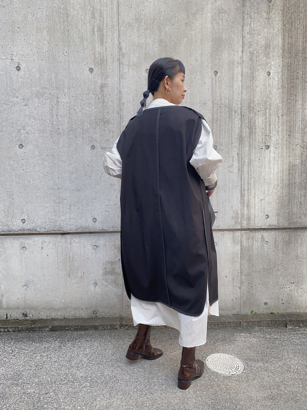 ブラック系のその他アウター、ホワイト系のシャツワンピース、ブラウン系のブーツを着用したレディースの秋コーディネートの3枚目の写真