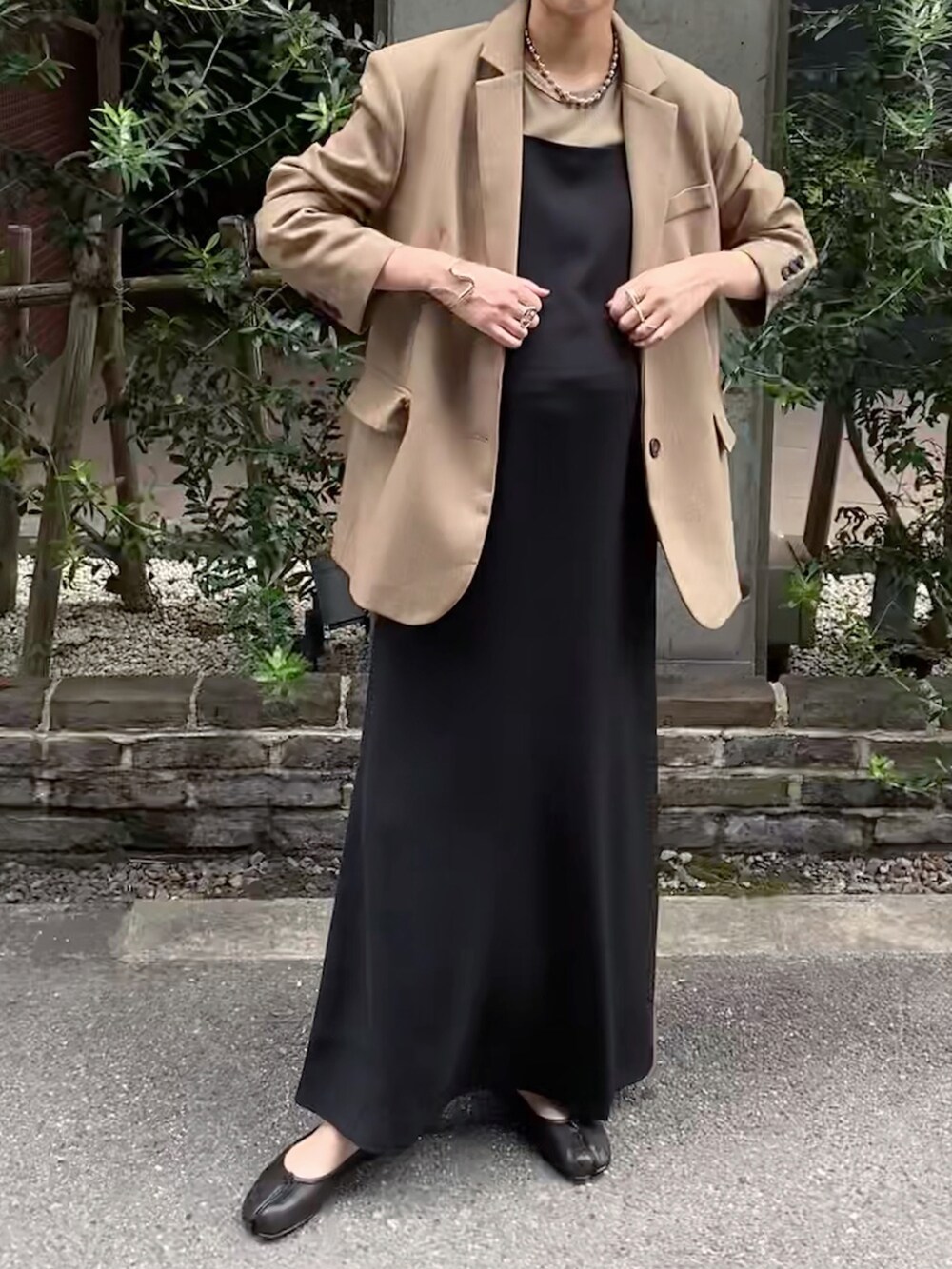 ベージュ系のテーラードジャケット、ブラック系のバレエシューズ、ブラック系のワンピースを着用したレディースの秋コーディネートの2枚目の写真