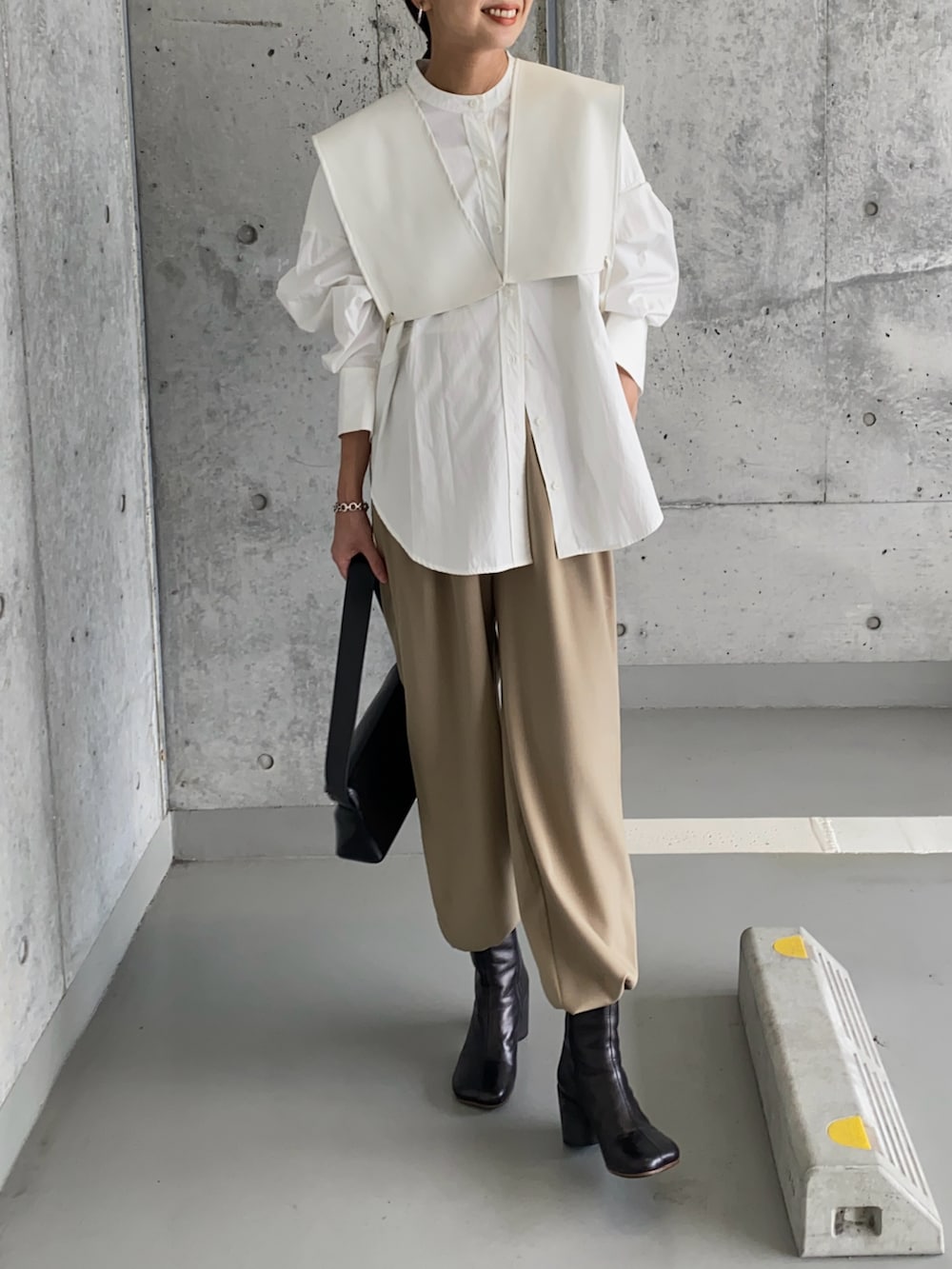 ホワイト系のベスト、ブラック系のブーツ、ブラック系のショルダーバッグを着用したレディースの春コーディネートの3枚目の写真