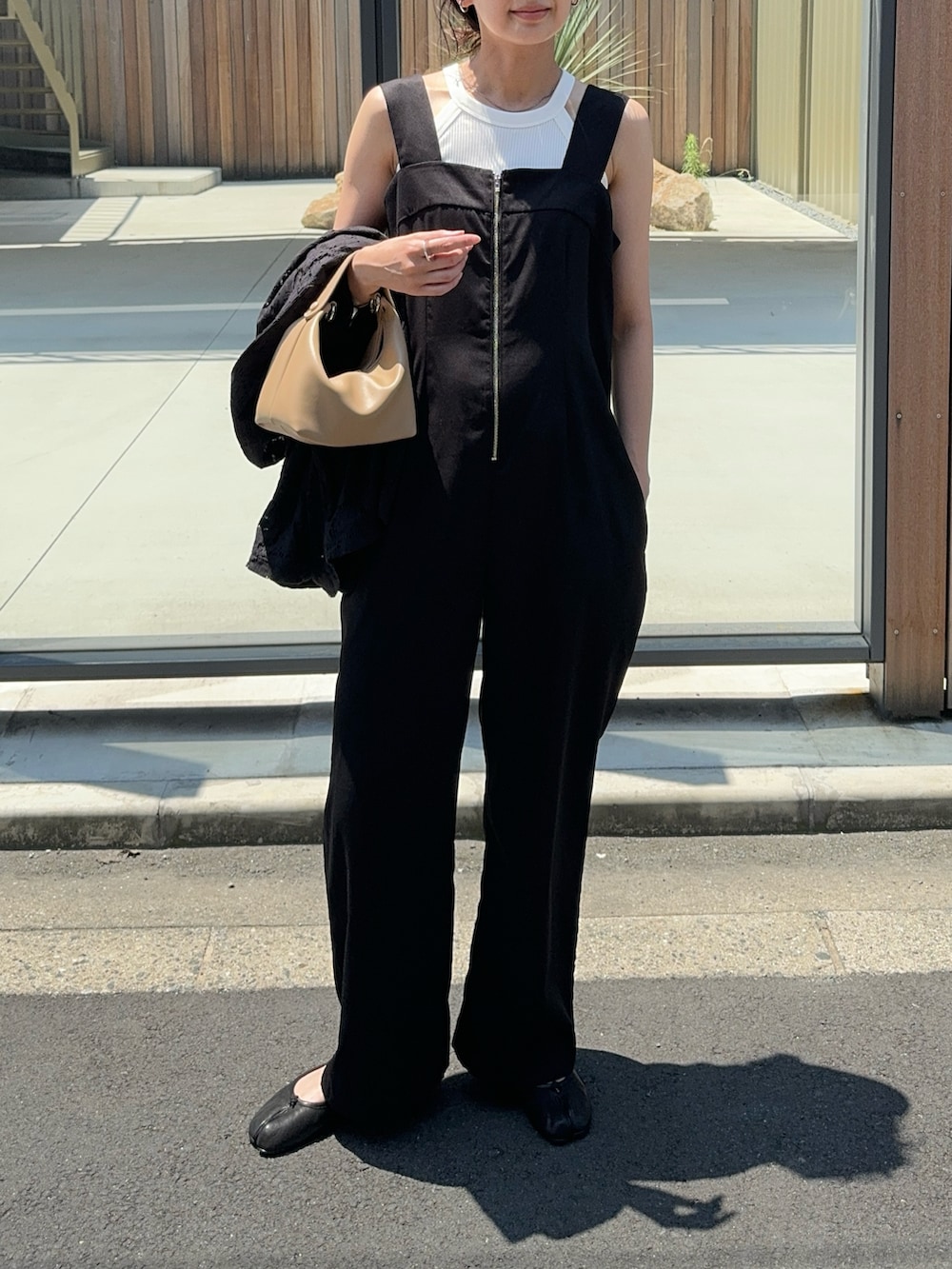 ブラック系のサロペット/オーバーオール、ホワイト系のタンクトップ、ブラック系のバレエシューズを着用したレディースの夏コーディネートの3枚目の写真
