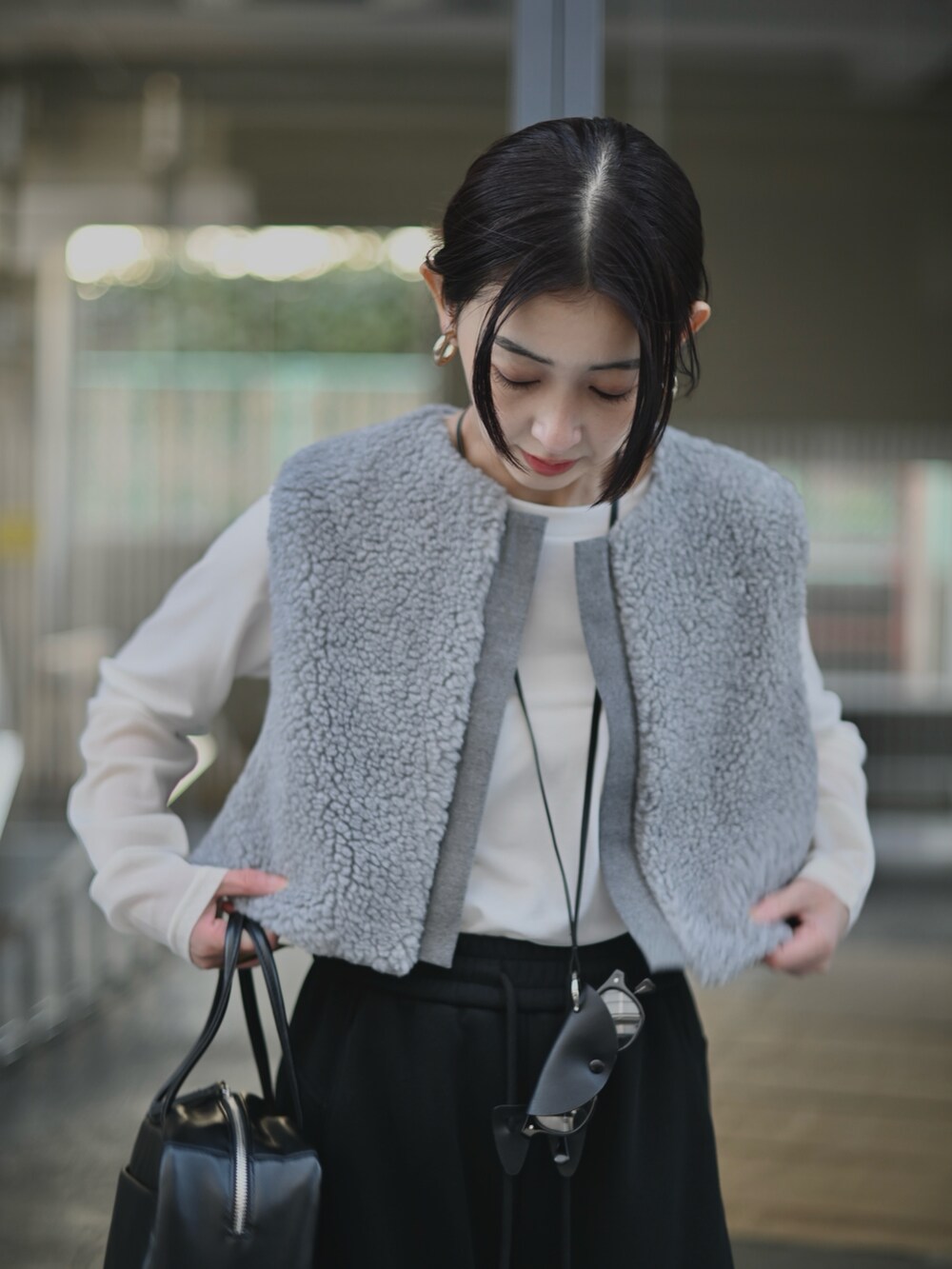 グレー系のベスト、ブラック系のスウェットパンツ、ブラック系のメガネを着用したレディースの冬コーディネートの3枚目の写真