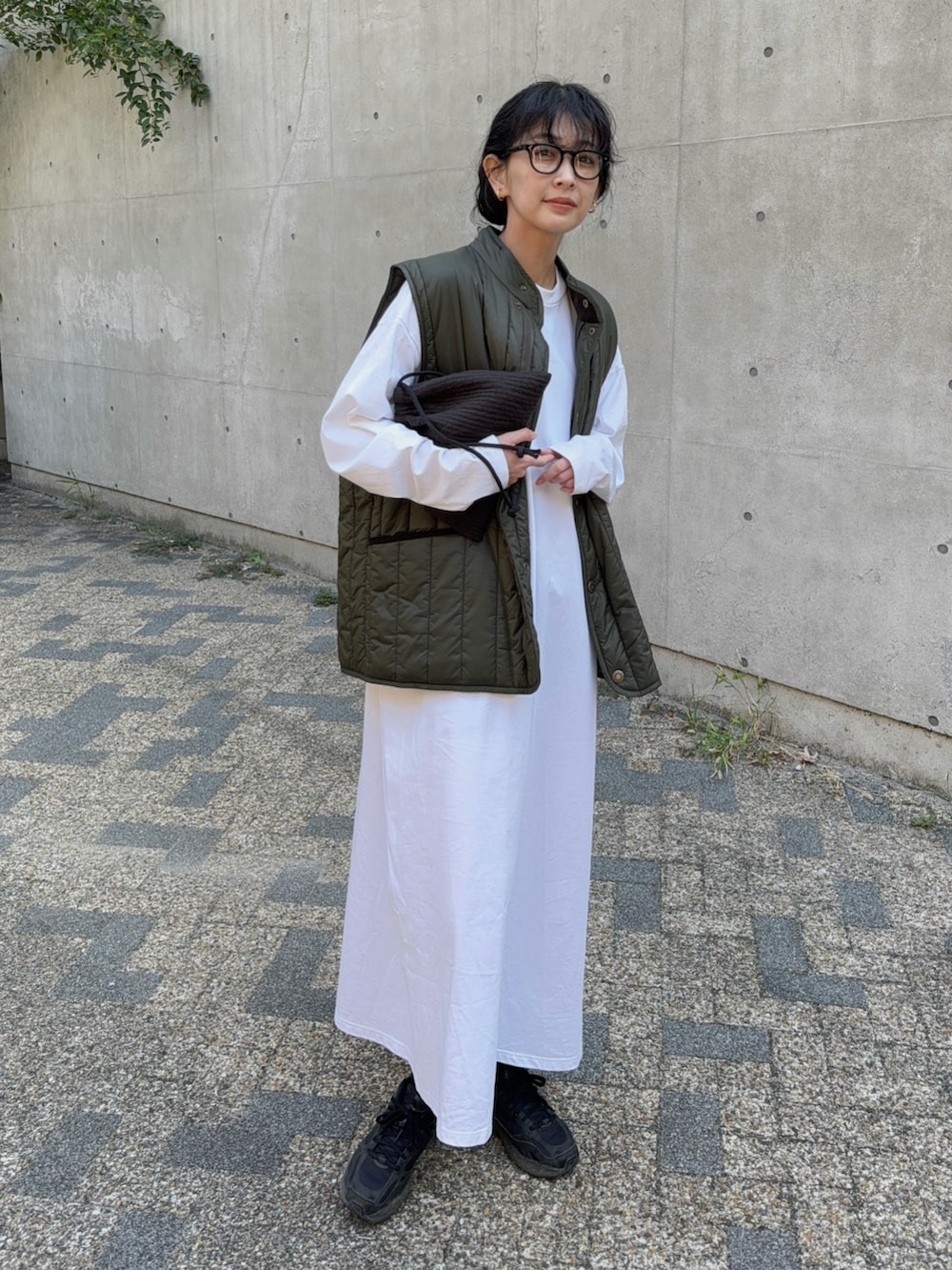 グリーン系のベスト、ブラック系のスニーカー、ブラック系のショルダーバッグを着用したレディースの秋コーディネートの4枚目の写真