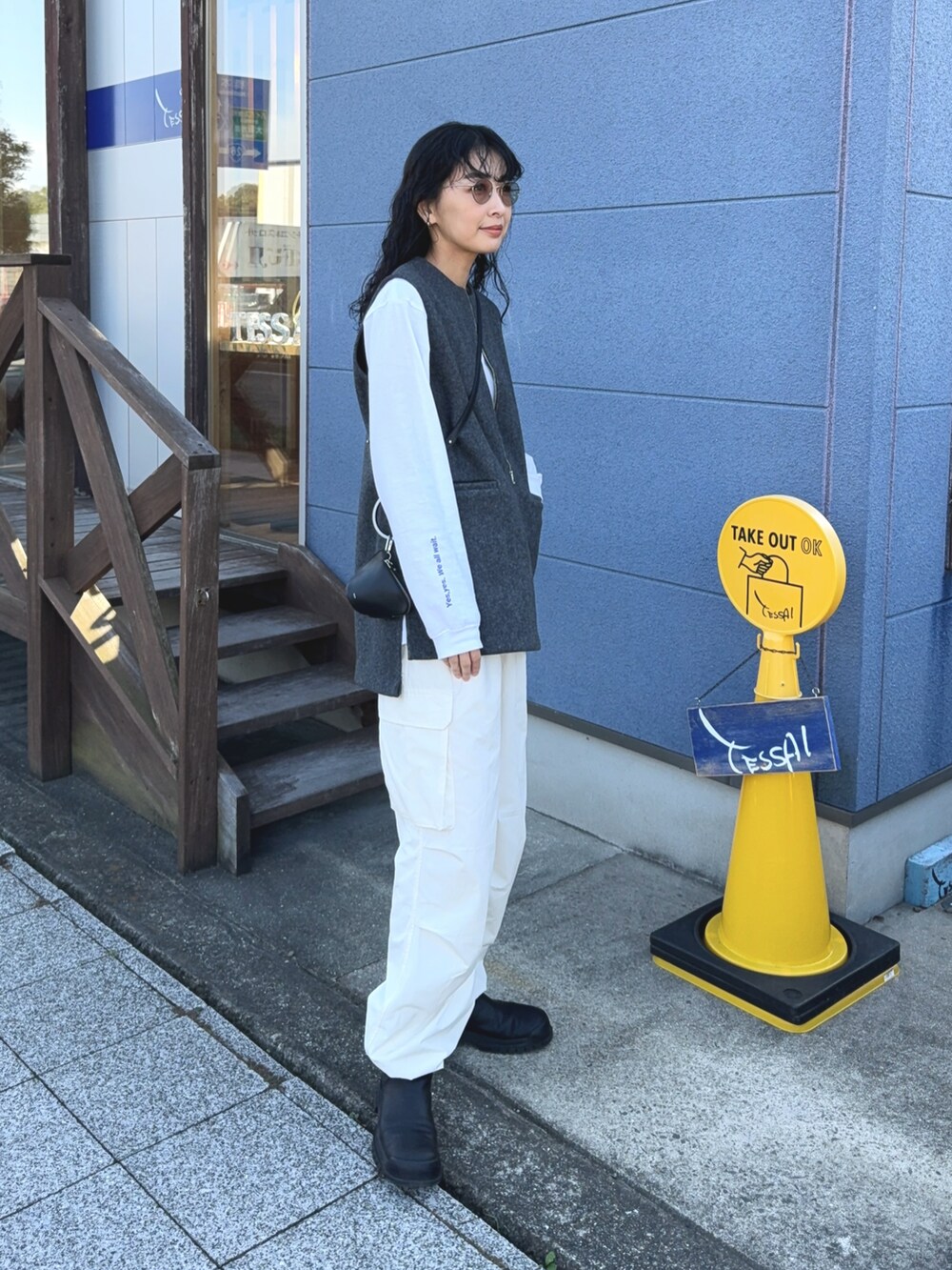 グレー系のベスト、ホワイト系のカーゴパンツ、ブラック系のショルダーバッグを着用したレディースの冬コーディネートの2枚目の写真