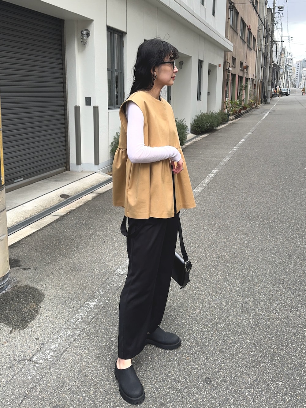 ベージュ系のベスト、ブラック系のショルダーバッグ、ブラック系のスラックスを着用したレディースの春コーディネートの2枚目の写真