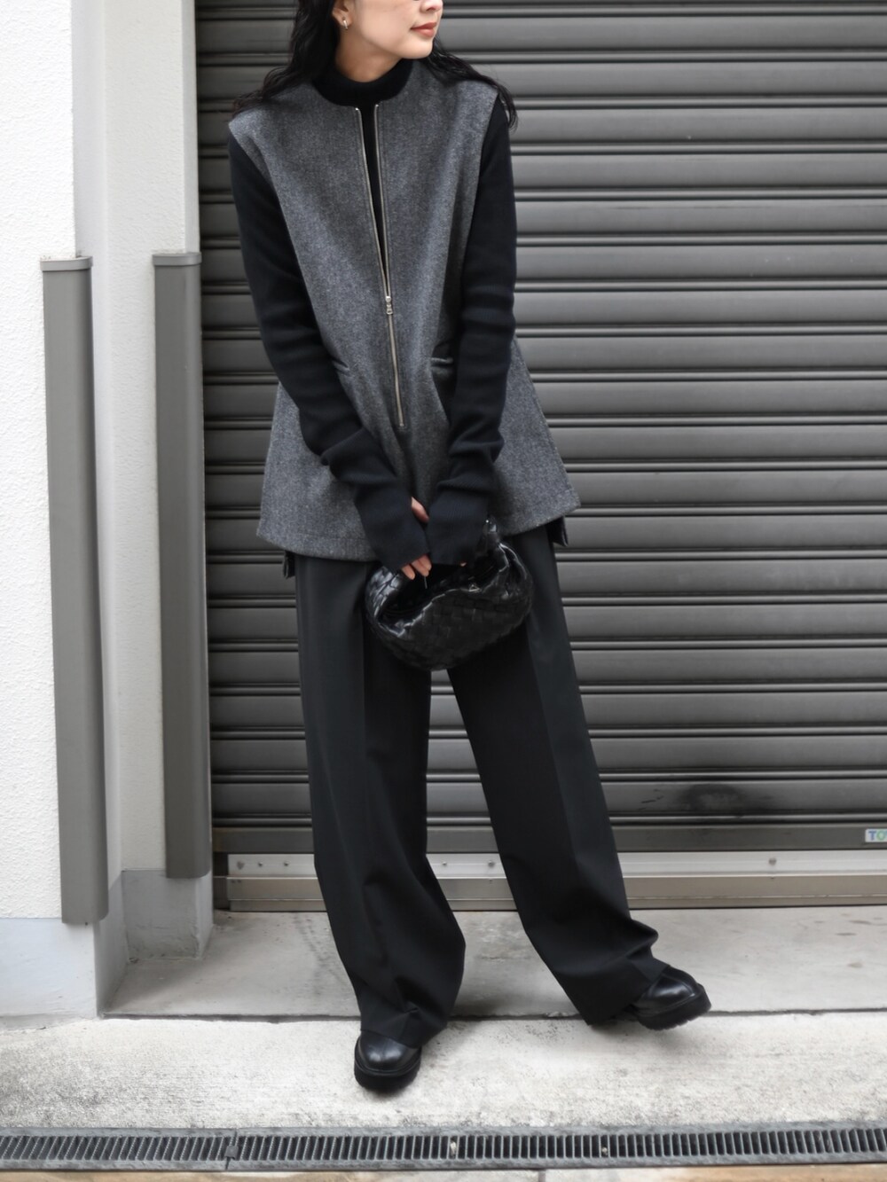 グレー系のベスト、ブラック系のスラックス、ブラック系のブーツを着用したレディースの冬コーディネートの4枚目の写真