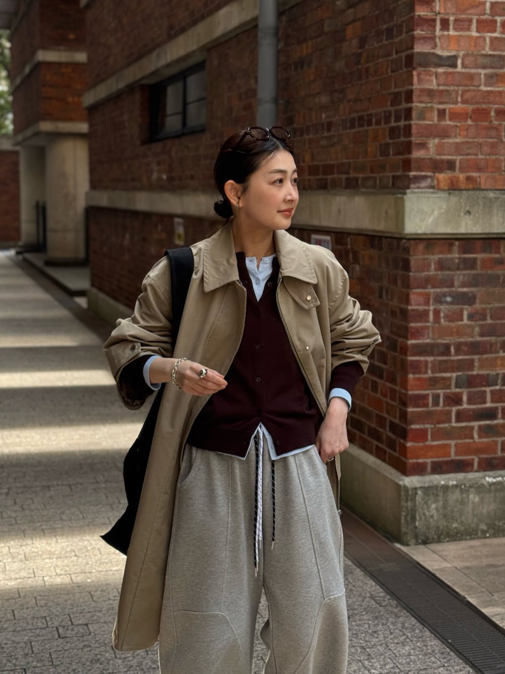 ブラック系のトートバッグ、ベージュ系のステンカラーコート、ブルー系のカーディガン/ボレロを着用したレディースの春コーディネートの3枚目の写真