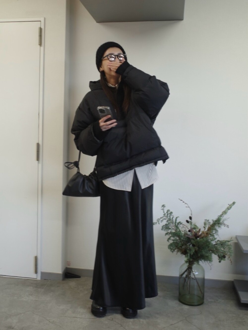 ブラック系のダウンジャケット/コート、ブラック系のブーツ、ブラック系のスカートを着用したレディースの冬コーディネートの2枚目の写真