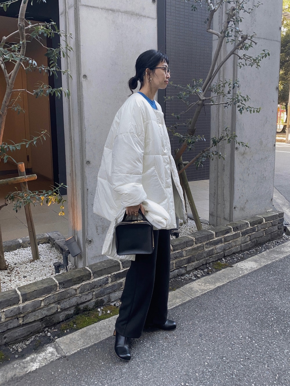 ホワイト系のダウンジャケット/コート、ブルー系のニット/セーター、ブラック系のサロペット/オーバーオールを着用したレディースの秋コーディネートの3枚目の写真