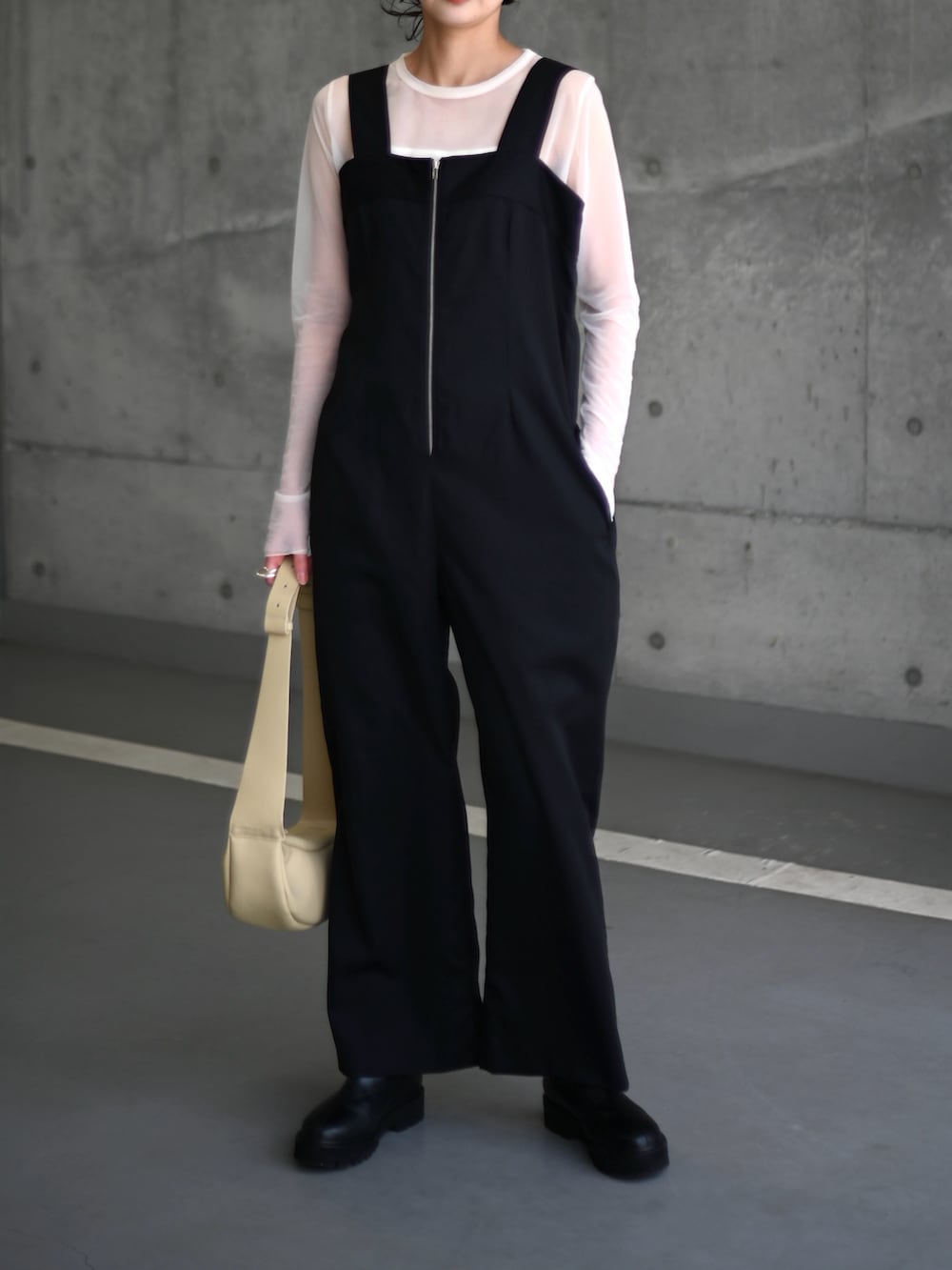 ブラック系のサロペット/オーバーオール、ホワイト系のキャミソール、ベージュ系のショルダーバッグを着用したレディースの春コーディネートの2枚目の写真