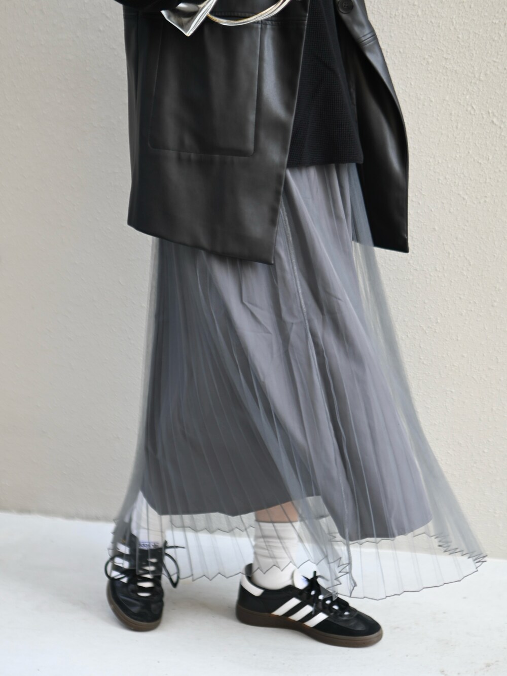 ブラック系のスカート、シルバー系のショルダーバッグ、ブラック系のスニーカーを着用したレディースの春コーディネートの5枚目の写真