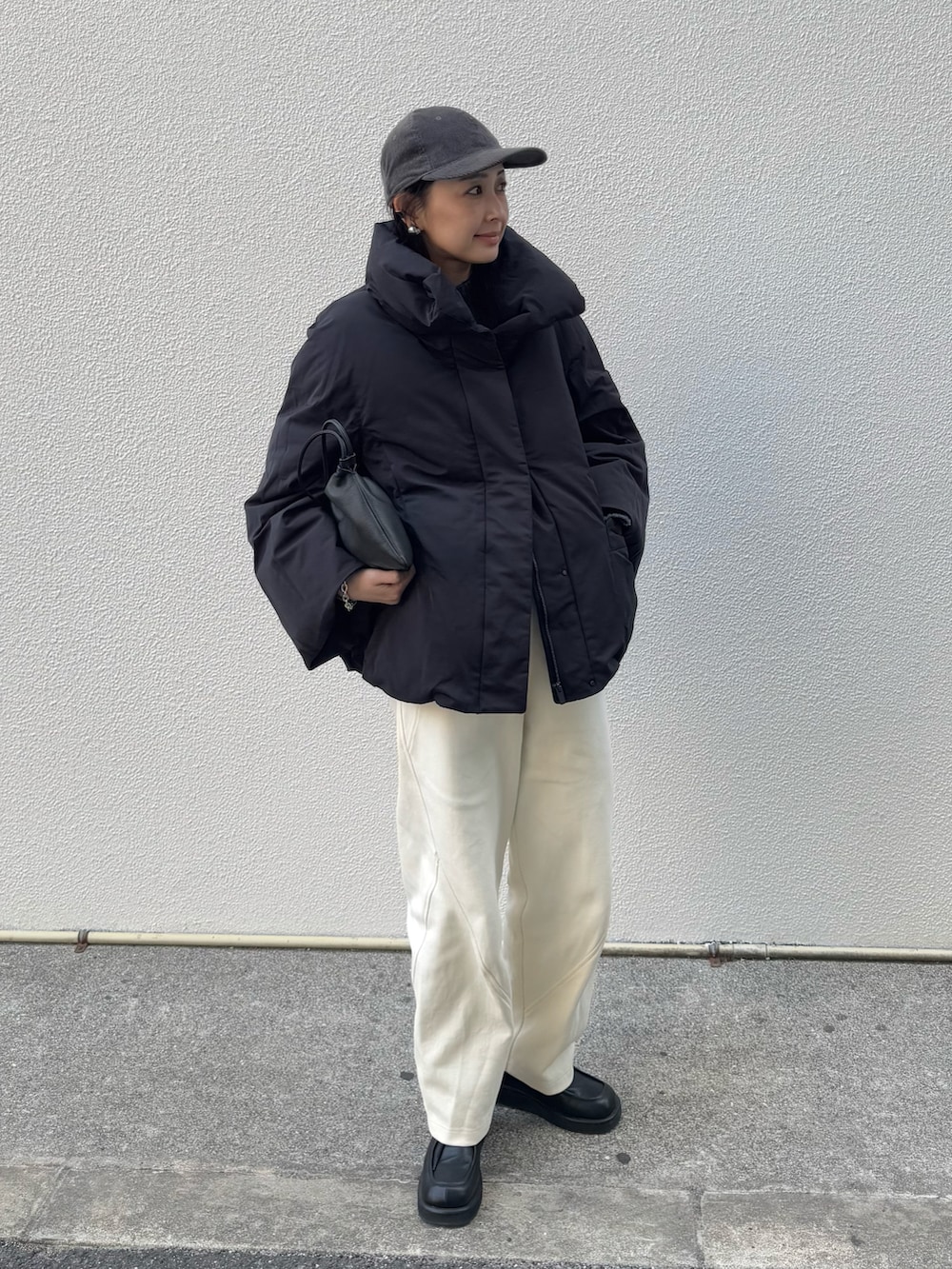 ブラック系のダウンジャケット/コート、ホワイト系のスウェットパンツ、ブラック系のローファーを着用したレディースの冬コーディネートの2枚目の写真