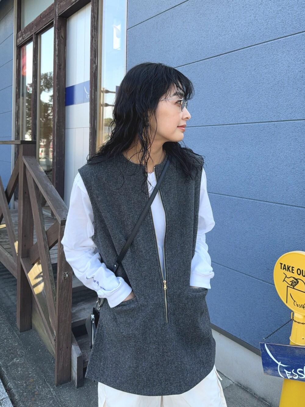 グレー系のベスト、ホワイト系のカーゴパンツ、ブラック系のショルダーバッグを着用したレディースの冬コーディネートの3枚目の写真