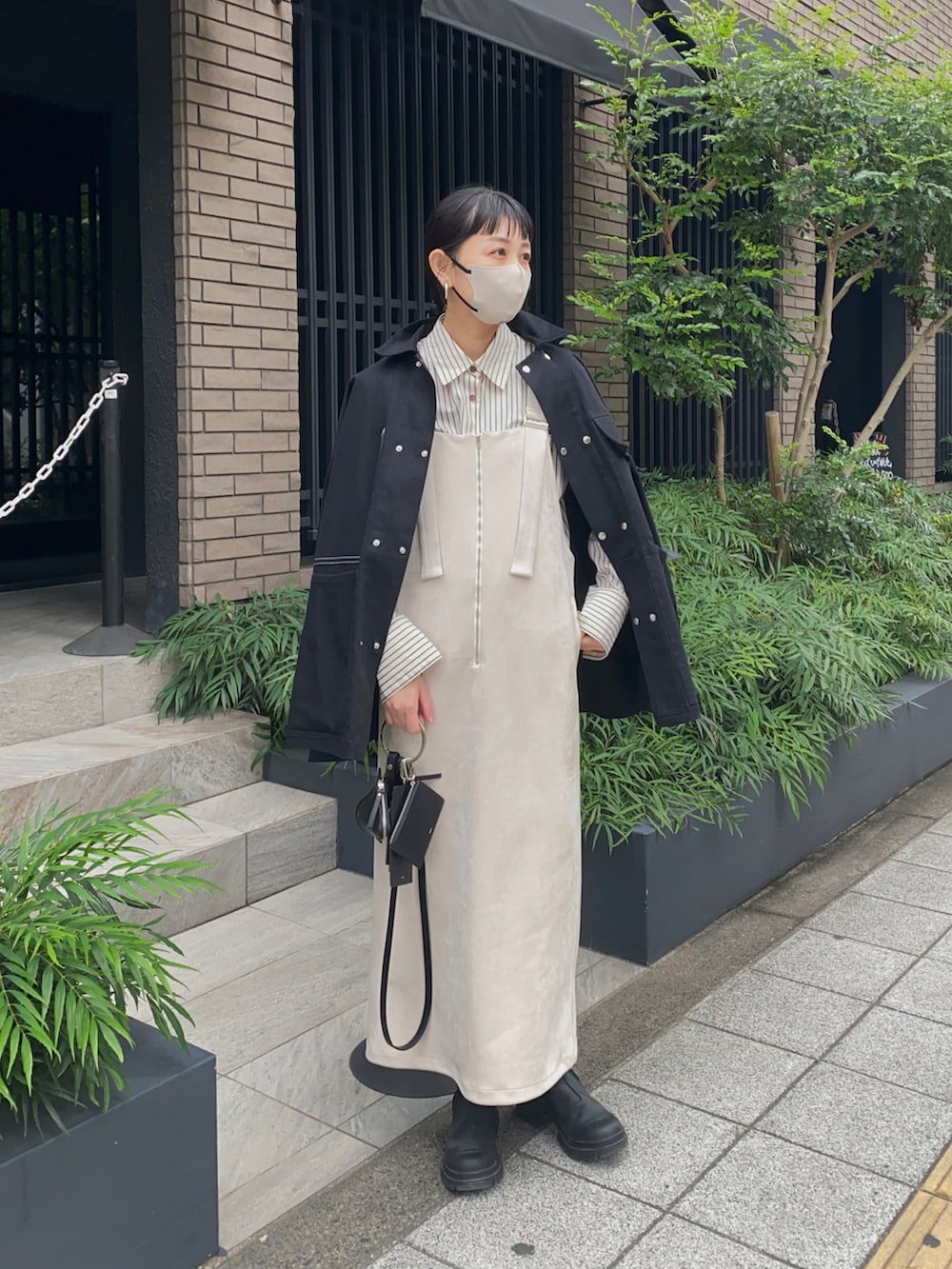 ホワイト系のジャンパースカート、ブラック系のジャケット/アウター、ブラック系のブーツを着用したレディースの秋コーディネートの4枚目の写真