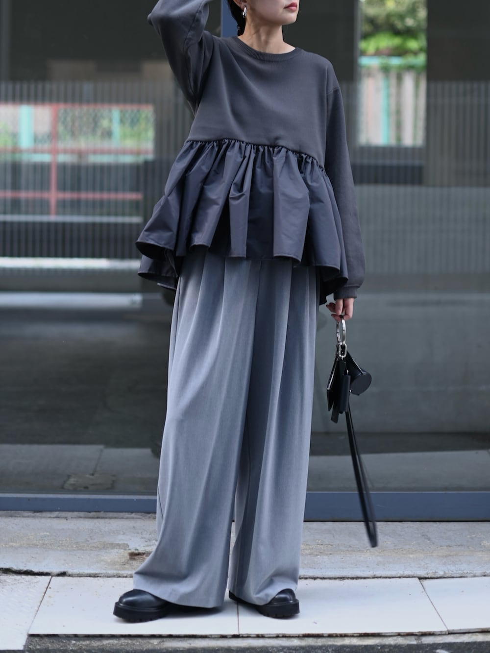 グレー系のニット/セーター、ブラック系のショルダーバッグ、グレー系のスラックスを着用したレディースの秋コーディネートの3枚目の写真