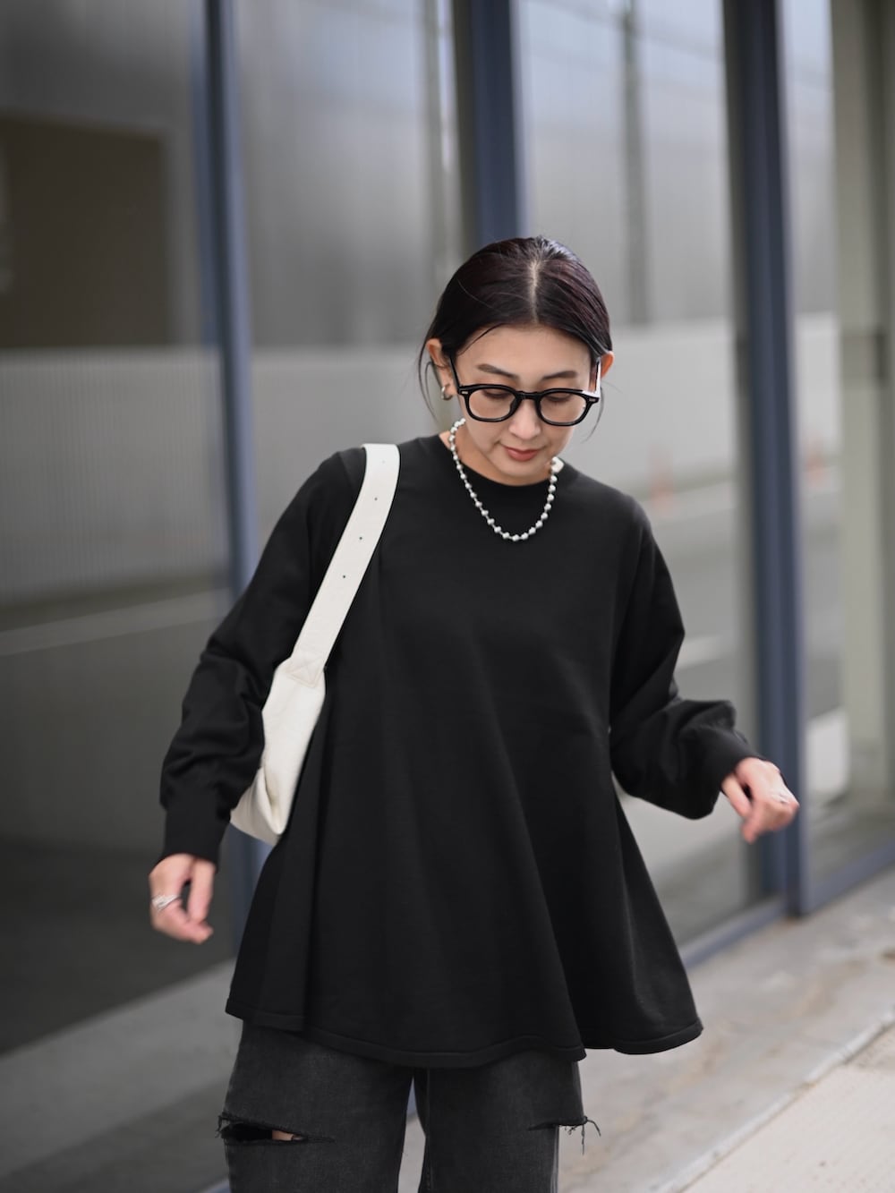 ブラック系のニット/セーター、ブラック系のデニムパンツ、ホワイト系のショルダーバッグを着用したレディースの秋コーディネートの4枚目の写真