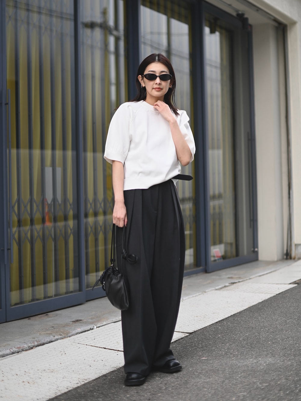 ホワイト系のニット/セーター、グレー系のその他パンツ、ブラック系のローファーを着用したレディースの夏コーディネートの3枚目の写真