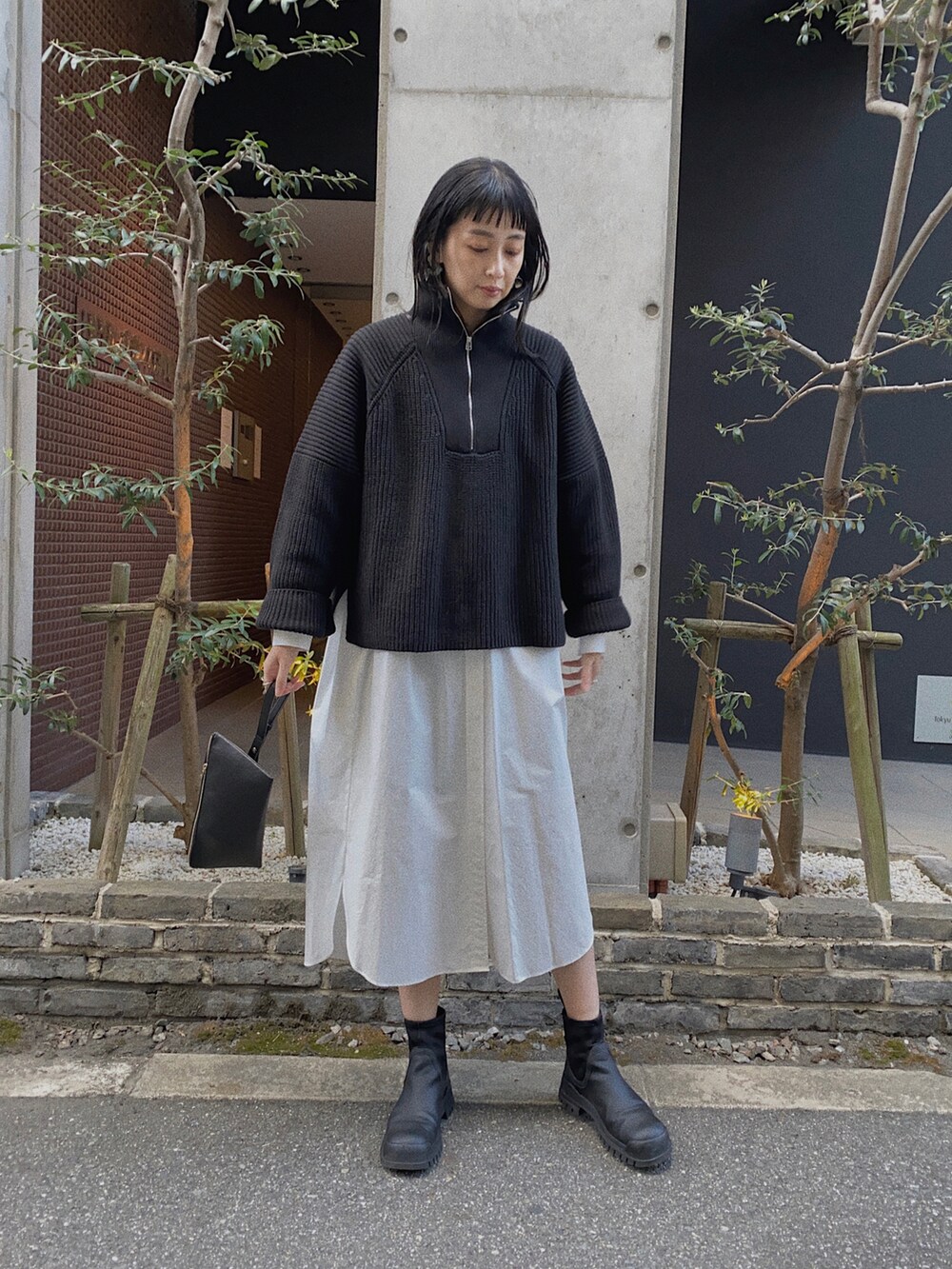 ブラック系のニット/セーター、ホワイト系のシャツワンピース、ブラック系のショルダーバッグを着用したレディースの秋コーディネートの2枚目の写真