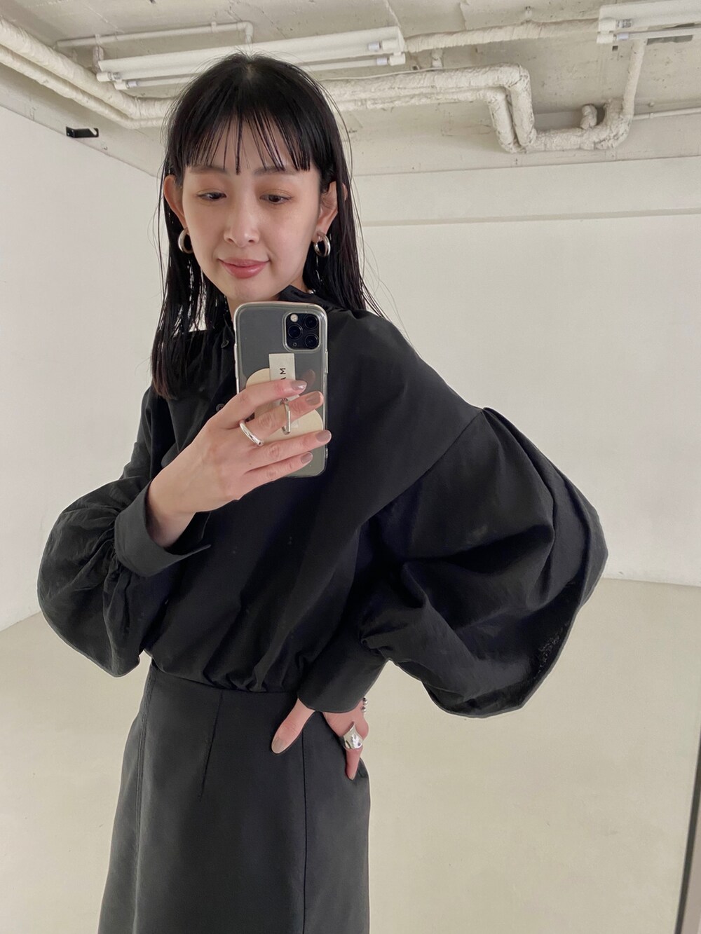 ブラック系のシャツ/ブラウス、ブラック系のスカート、ブルー系のハンドバッグを着用したレディースの春コーディネートの3枚目の写真