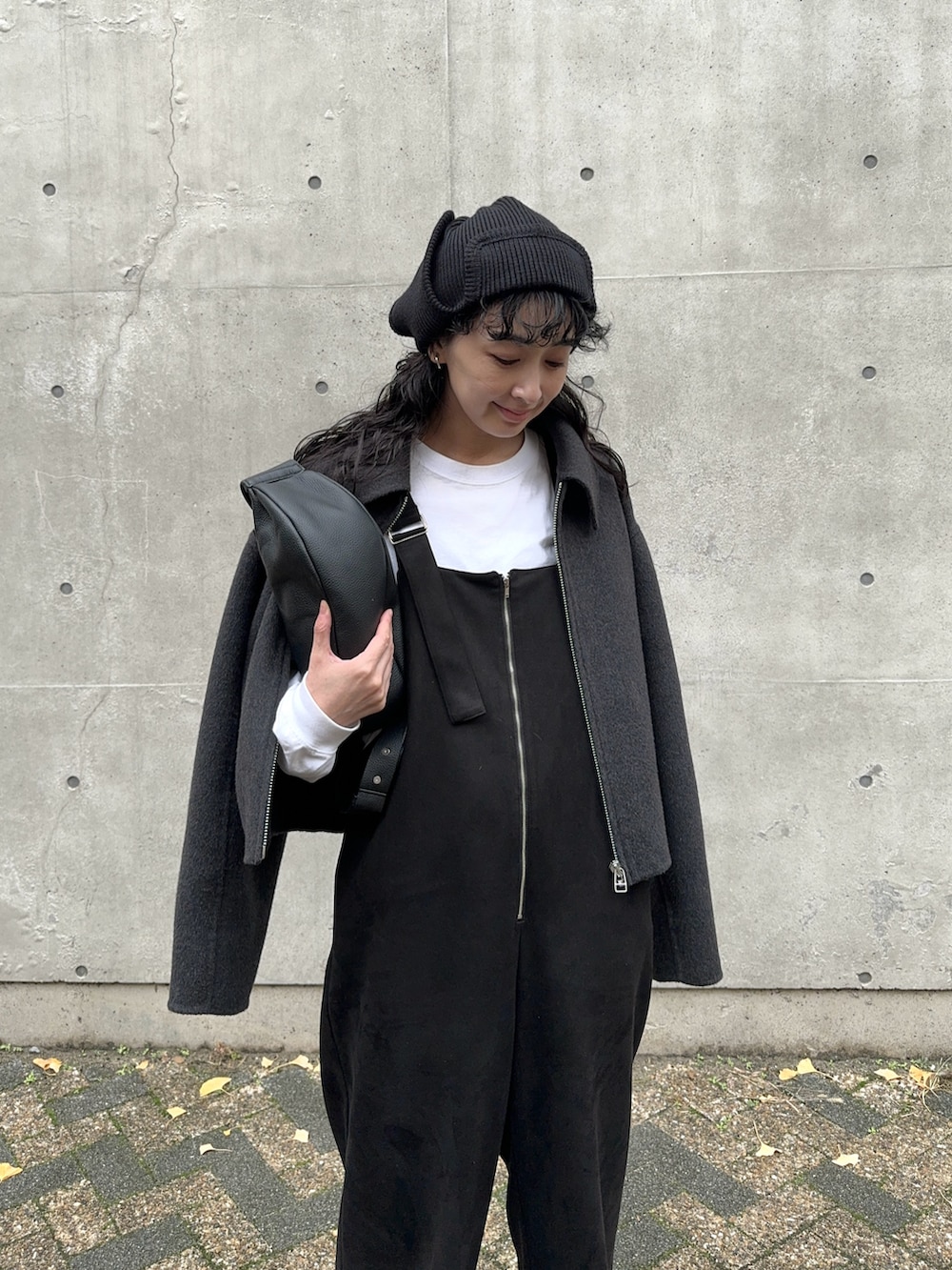 グレー系のブルゾン、ブラック系のサロペット/オーバーオール、ホワイト系のTシャツ/カットソーを着用したレディースの冬コーディネートの2枚目の写真