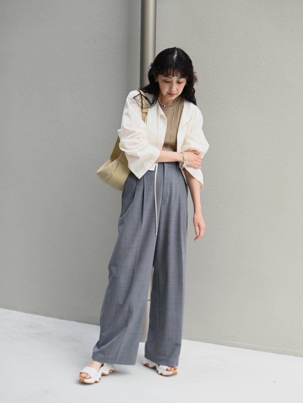 ホワイト系のシャツ/ブラウス、ベージュ系のショルダーバッグ、グレー系のスラックスを着用したレディースの春コーディネートの5枚目の写真