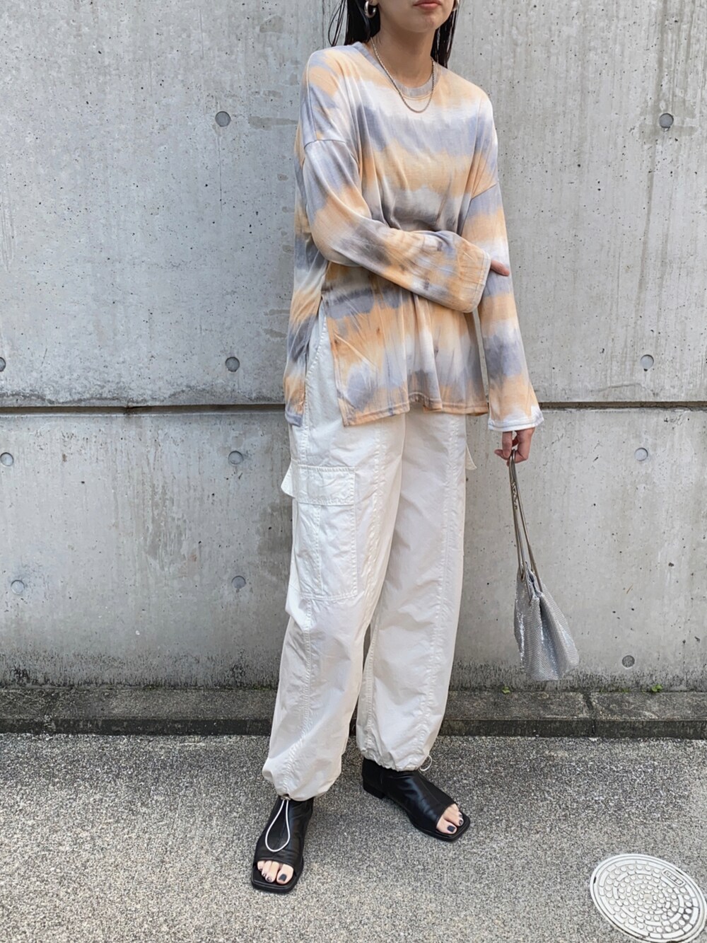 オレンジ系のTシャツ/カットソー、ホワイト系のその他パンツ、シルバー系のショルダーバッグを着用したレディースの春コーディネートの2枚目の写真