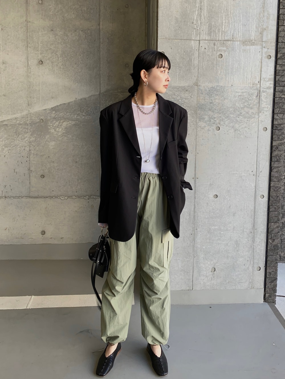 ブラック系のテーラードジャケット、ホワイト系のキャミソール、グリーン系のカーゴパンツを着用したレディースの春コーディネートの2枚目の写真