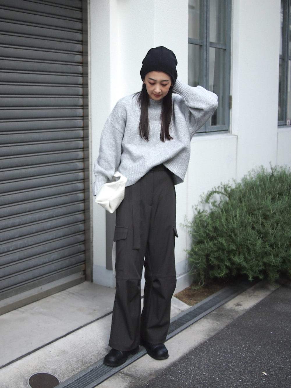 グレー系のニット/セーター、ホワイト系のショルダーバッグ、グレー系のパンツを着用したレディースの秋コーディネートの2枚目の写真