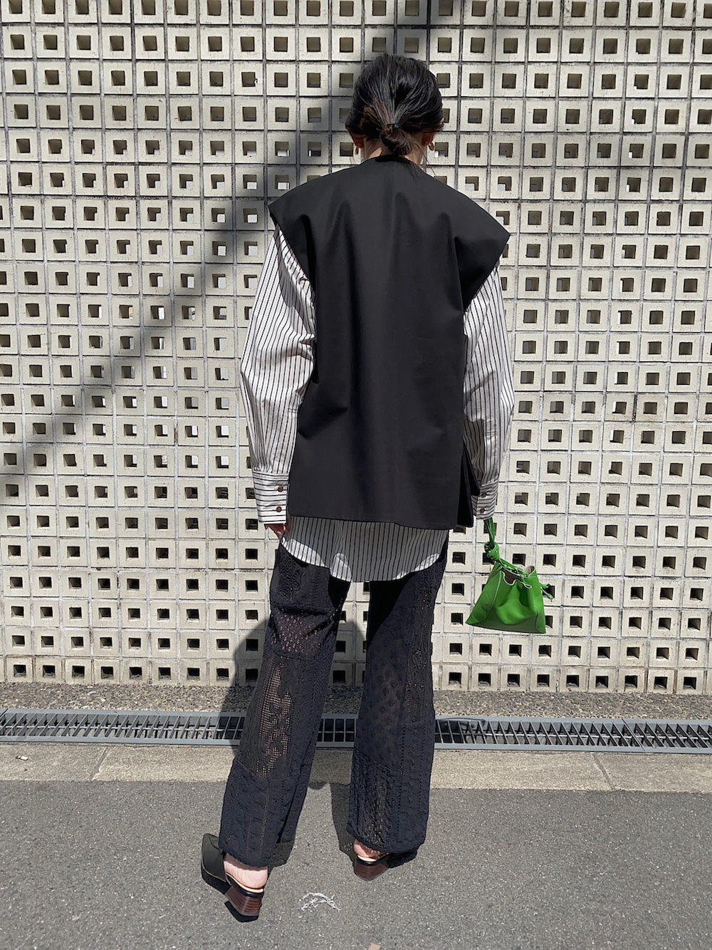 ブラック系のベスト、ベージュ系のシャツ/ブラウス、グリーン系のハンドバッグを着用したレディースの春コーディネートの4枚目の写真