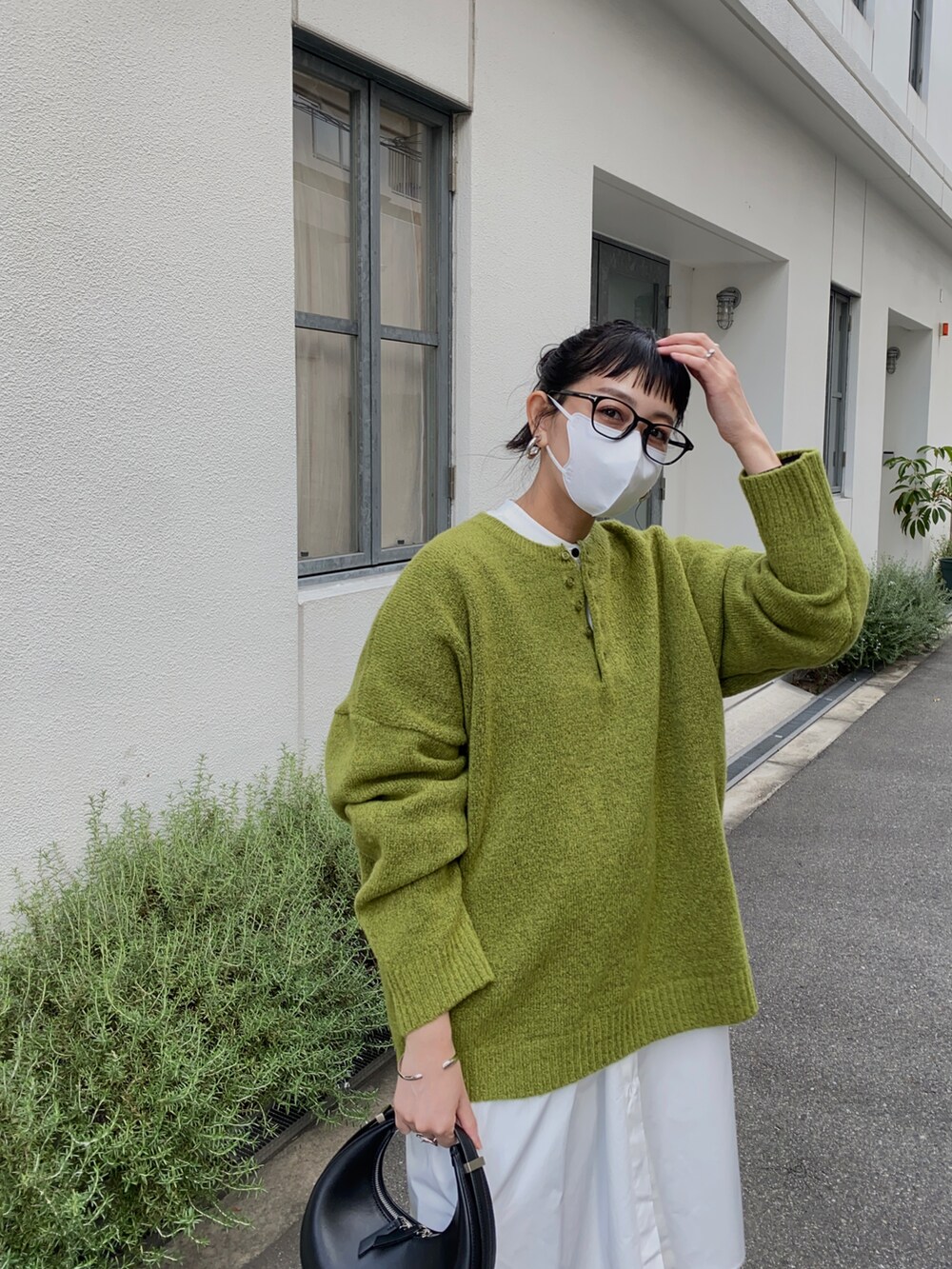 グリーン系のニット/セーター、ホワイト系のシャツワンピースを着用したレディースの秋コーディネートの3枚目の写真