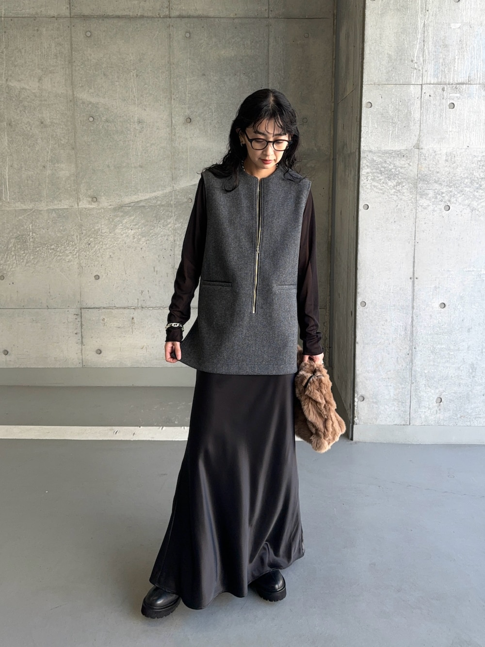 グレー系のベスト、ブラック系のTシャツ/カットソー、ブラック系のスカートを着用したレディースの秋コーディネートの3枚目の写真