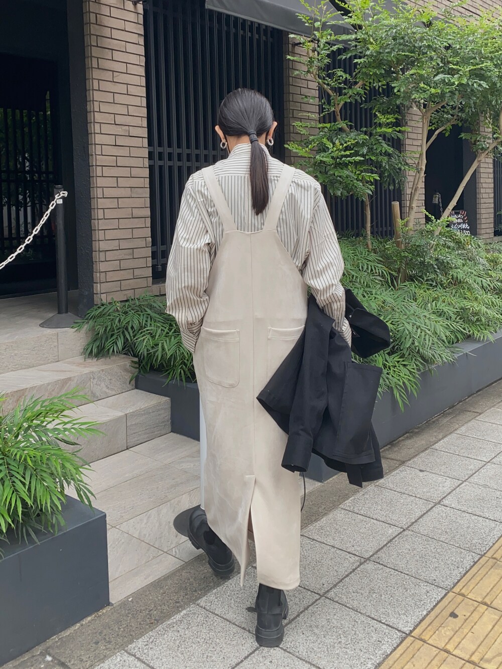 ホワイト系のジャンパースカート、ブラック系のジャケット/アウター、ブラック系のブーツを着用したレディースの秋コーディネートの3枚目の写真